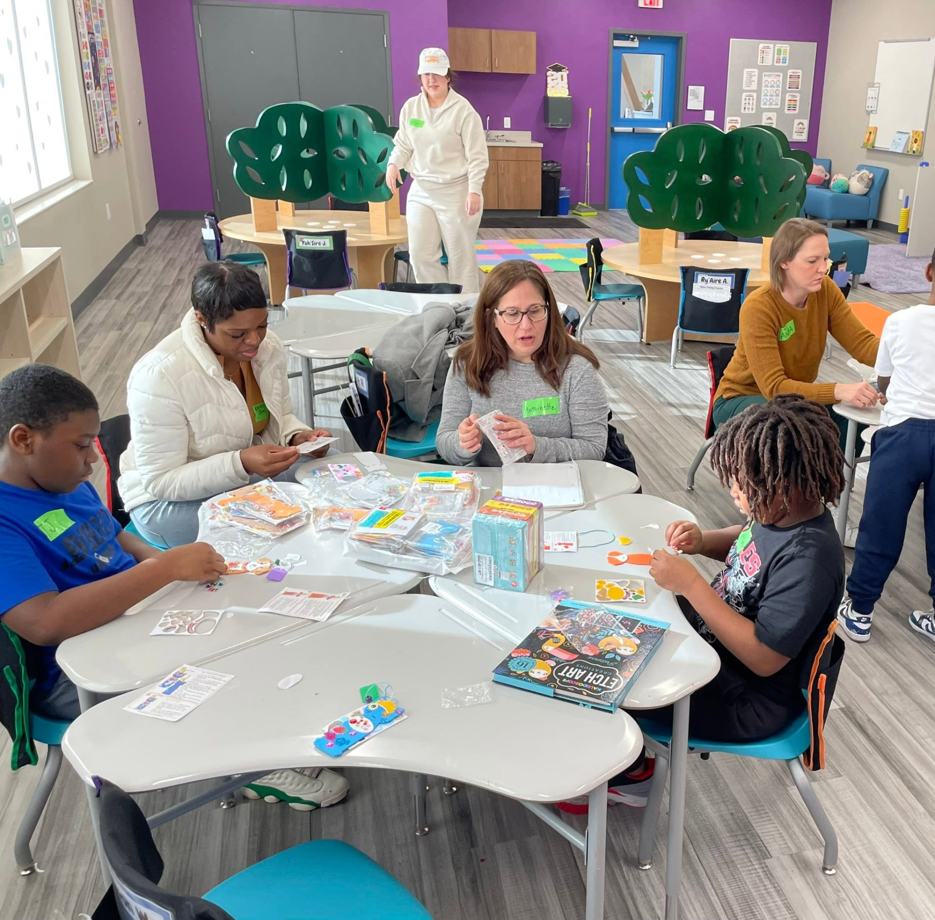 Volunteers and kids working on craft kits together in the activity room