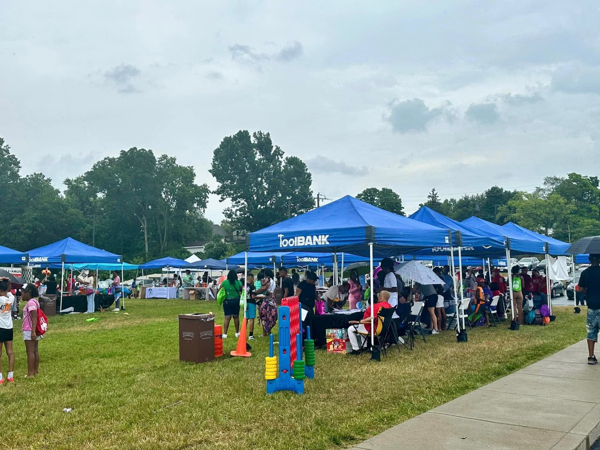 Row of blue ToolBank tents with families and giant Connect 4 game at 2nd KidsFest