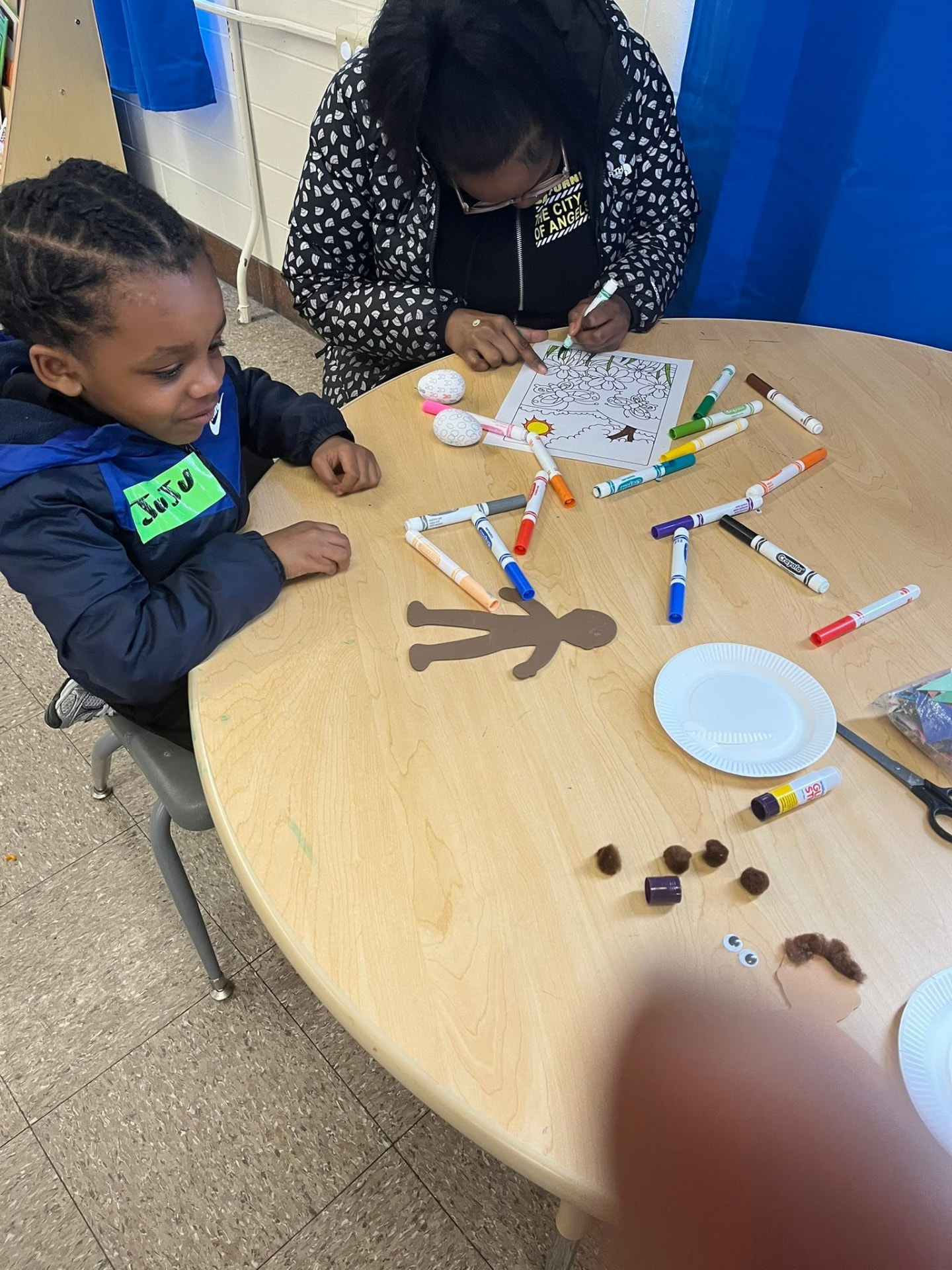 A young boy and a volunteer coloring and making crafts at the activity table