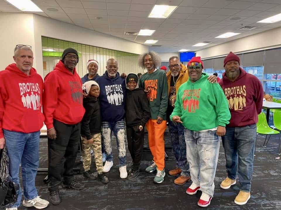 Group of Brothas Inc. mentors and youth posing together in Brothas hoodies at Jingle Jam 2024