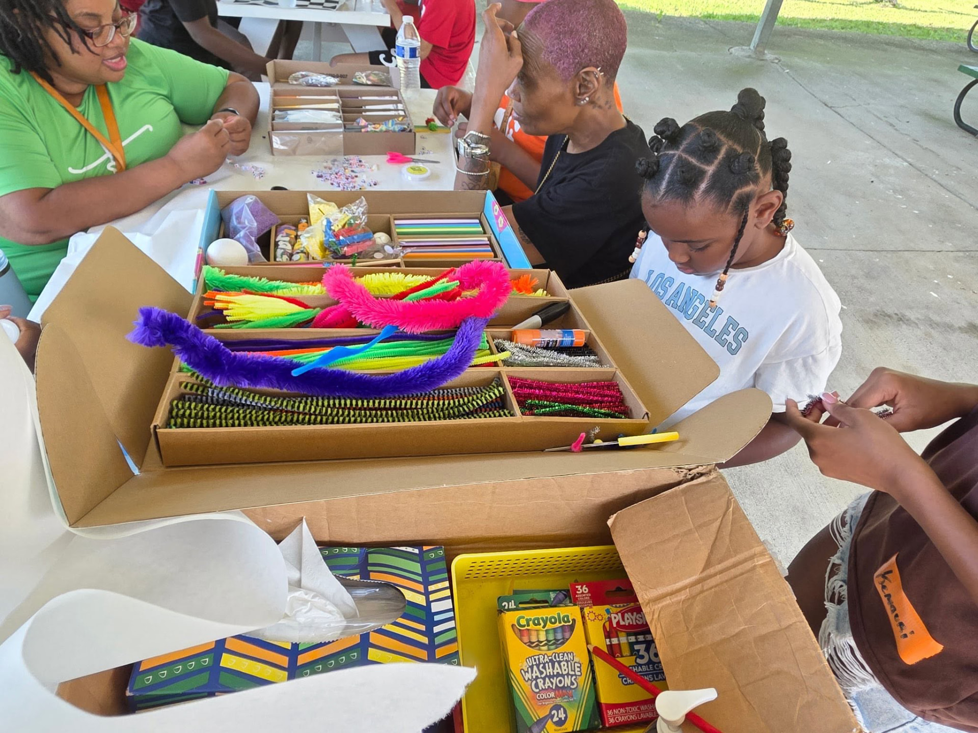 Kids and volunteers making crafts with pipe cleaners, beads and crayons at Saturday Hoops