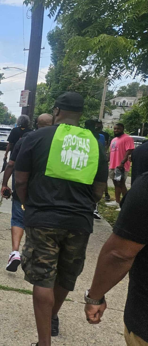 Brothas Inc. mentor in a bright green safety vest walking with the crew during a Black Family Reunion 2024 community walk