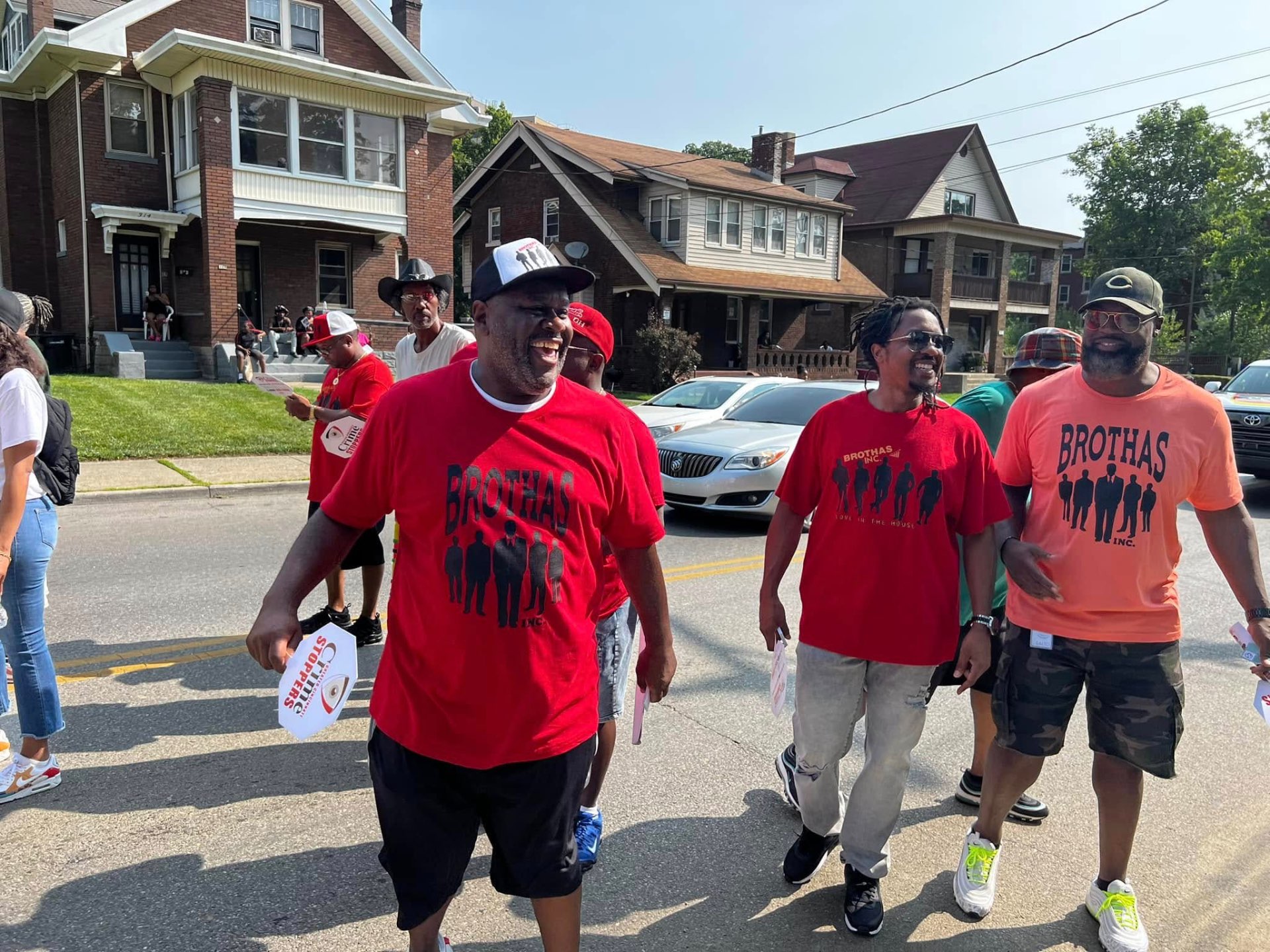 Brothas Inc. mentors in red shirts laughing together on the way to the Black Family Reunion Parade