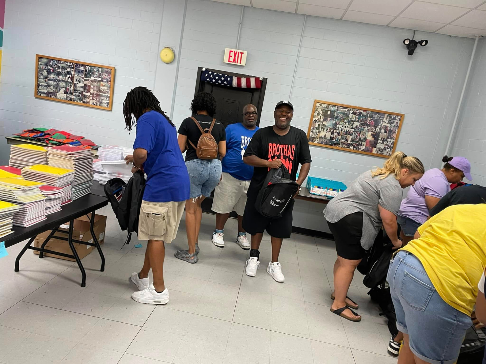 Volunteers packing notebooks and folders into backpacks at supply tables during the 2024 Backpack Giveaway