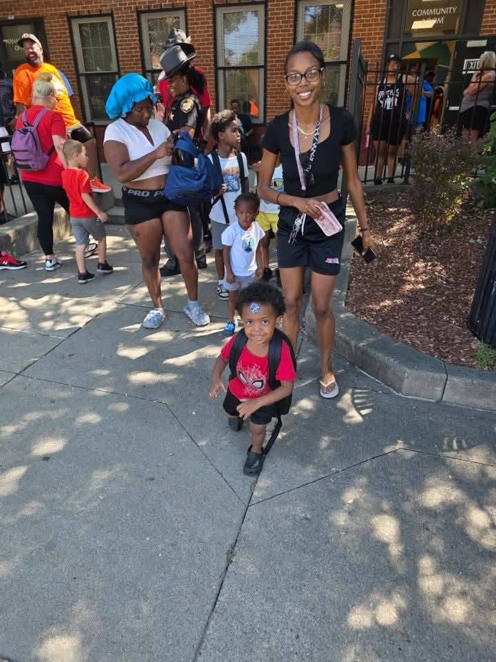 A mother and her young sons leaving the 2025 Backpack Giveaway with new backpacks