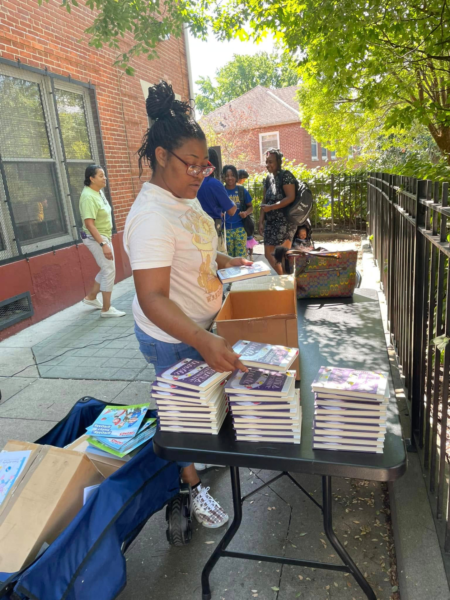 Volunteer arranging stacks of free children's books on a table at the 2024 Backpack Giveaway