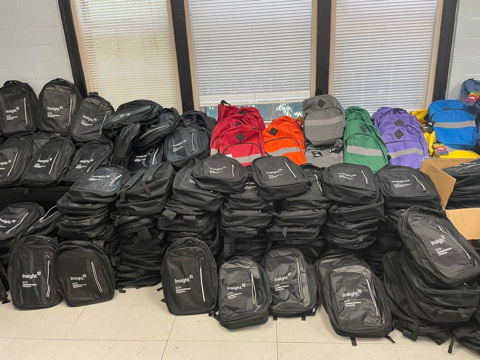 Hundreds of donated backpacks stacked and ready for distribution at the 2024 Backpack Giveaway