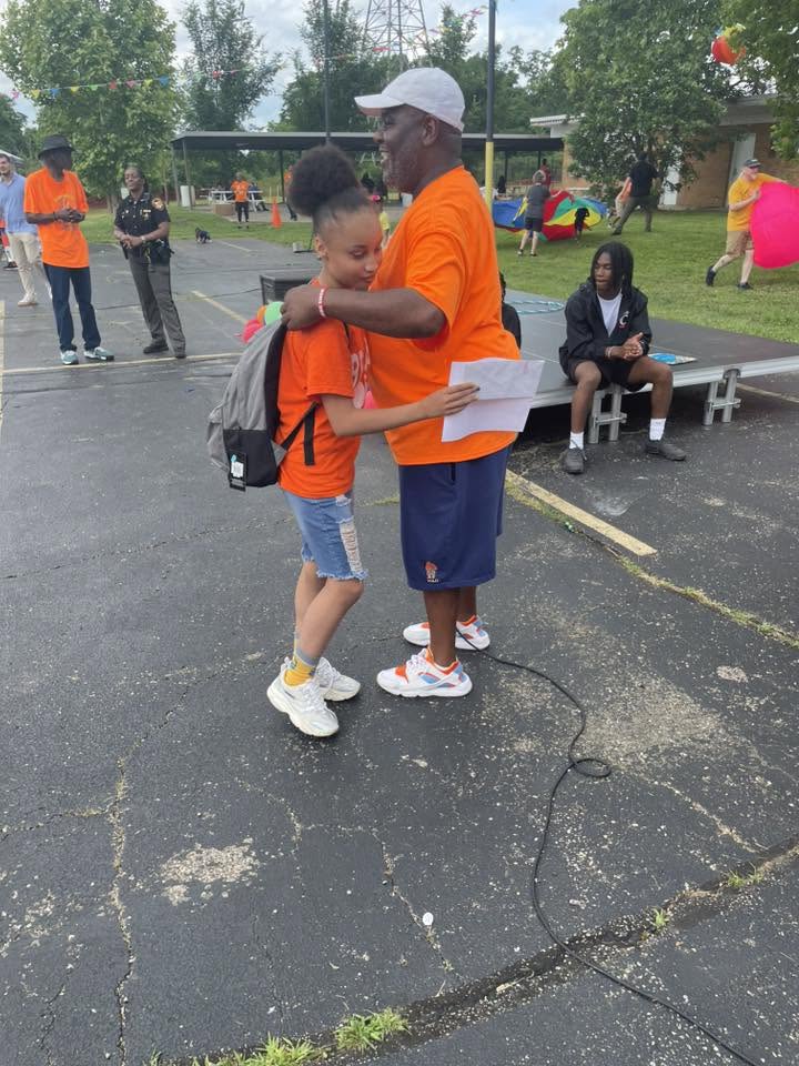Brothas Inc. founder awarding a backpack to a young student at 3rd KidsFest