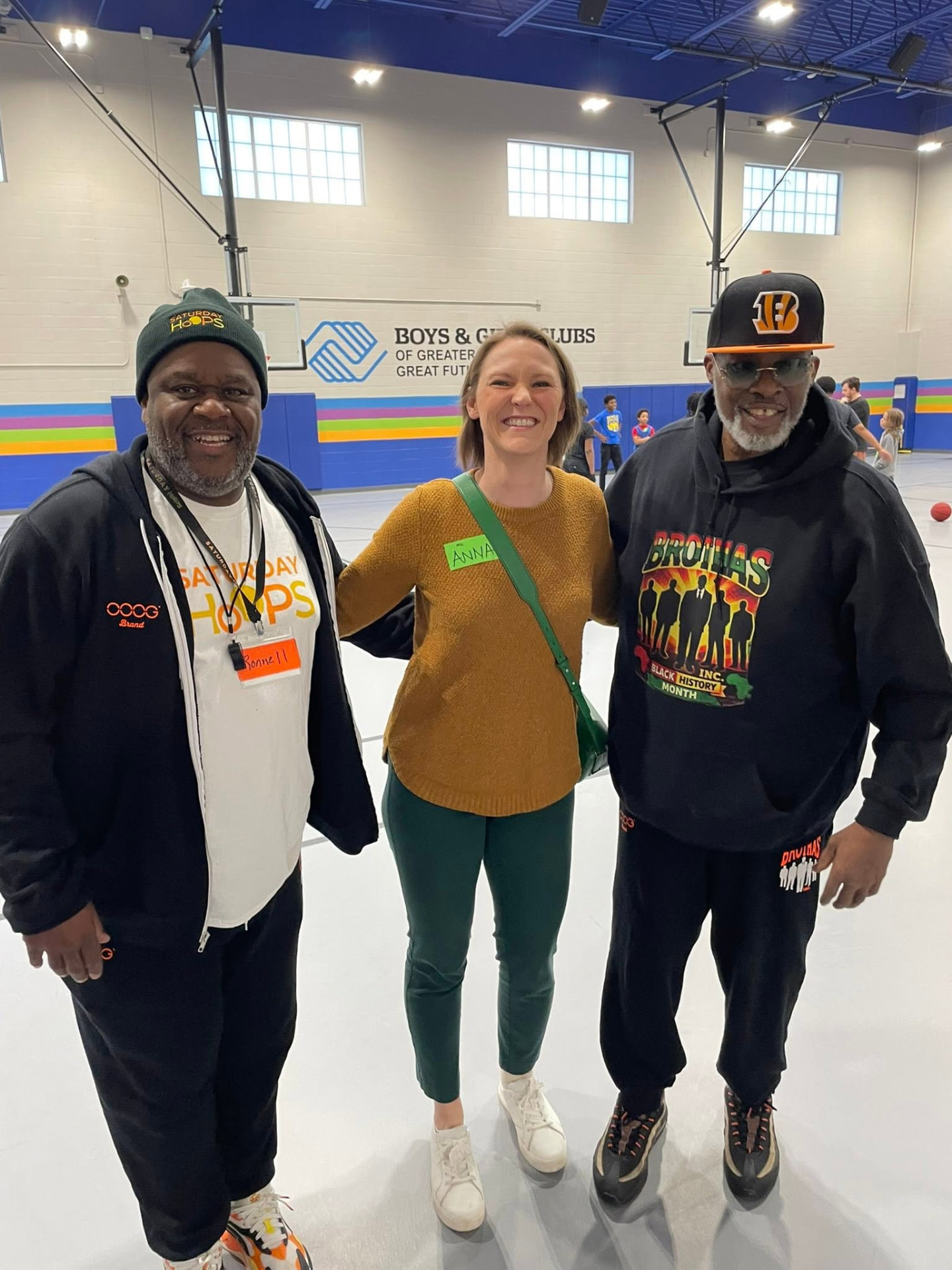 Two Brothas Inc. mentors and a volunteer smiling in the Boys & Girls Club gym