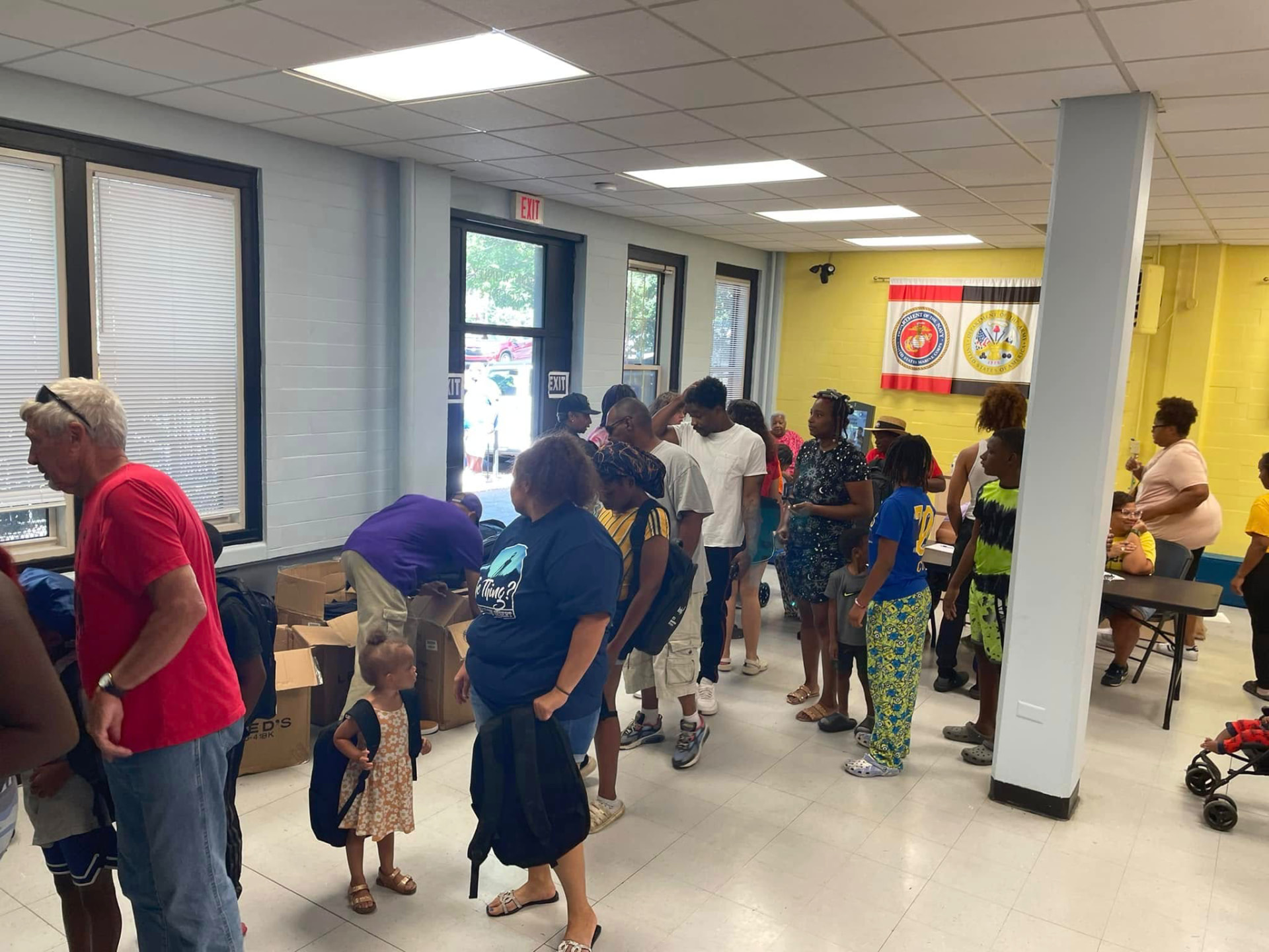 Families and children waiting in line inside the community room during the 2024 Backpack Giveaway