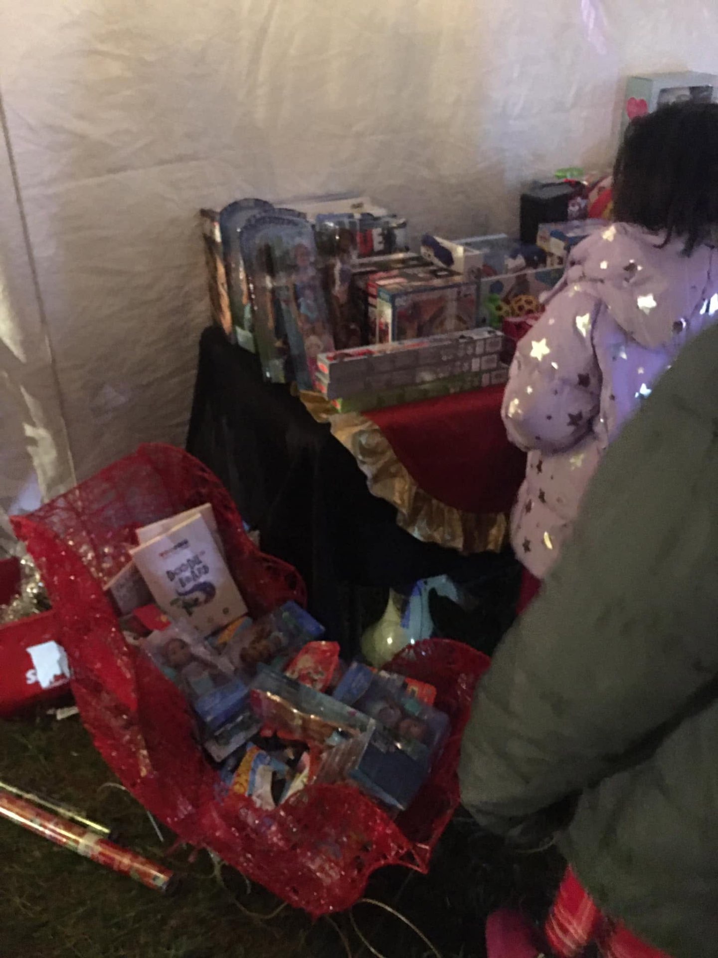 Child browsing a red sleigh overflowing with wrapped toys and games at Brothas Inc. Jingle Jam 2023