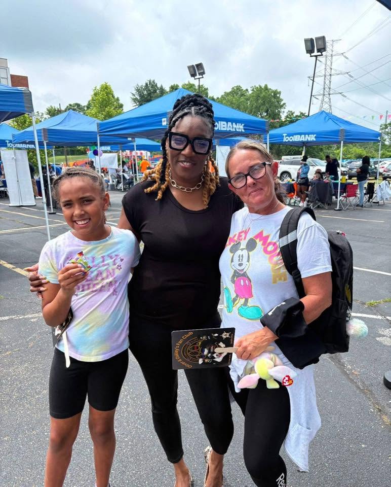 Volunteer with young girl and mom at the ToolBank tent village at 3rd KidsFest
