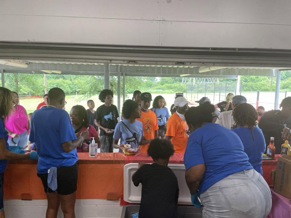 Volunteers in blue serving food to kids and families at 3rd KidsFest