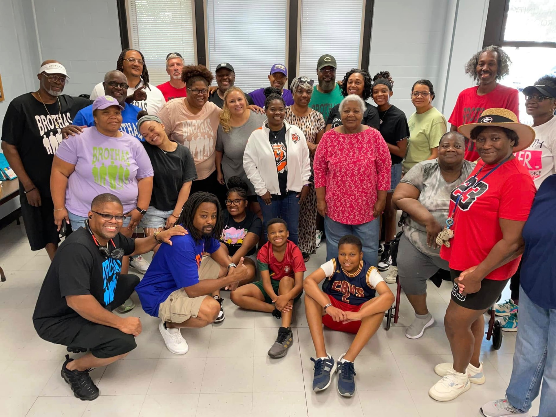 Large group of Brothas Inc. volunteers, families and youth posing together in Brothas Inc. shirts at the 2024 Backpack Giveaway