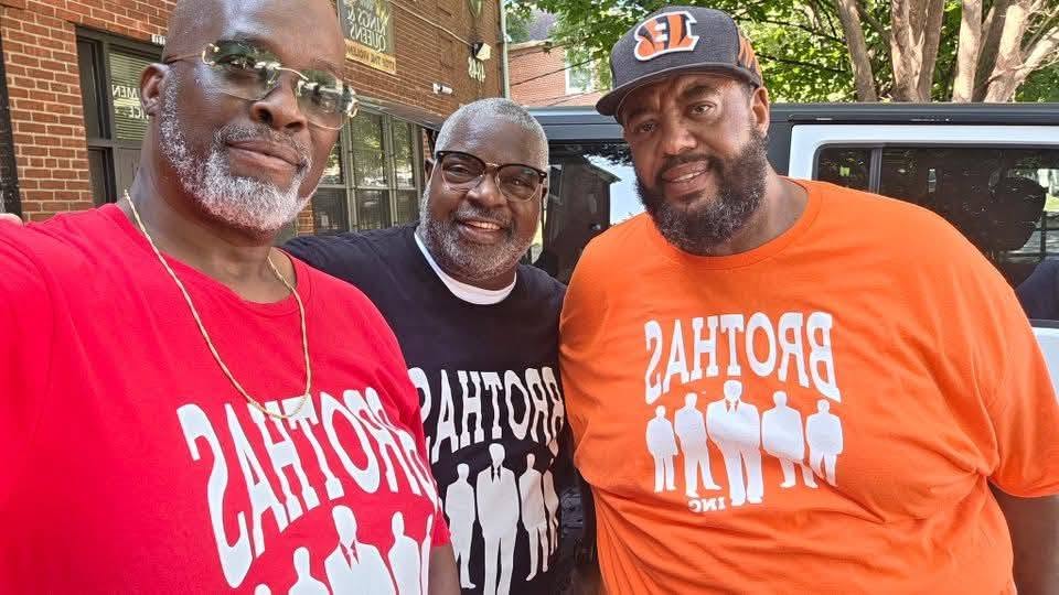 Three Brothas Inc. members in red, black and orange shirts posing at the 2025 Backpack Giveaway