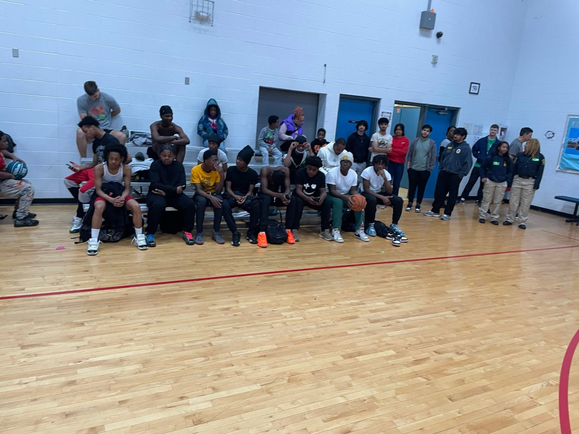 Teens gathered on the bleachers in the gym during a Saturday Hoops session
