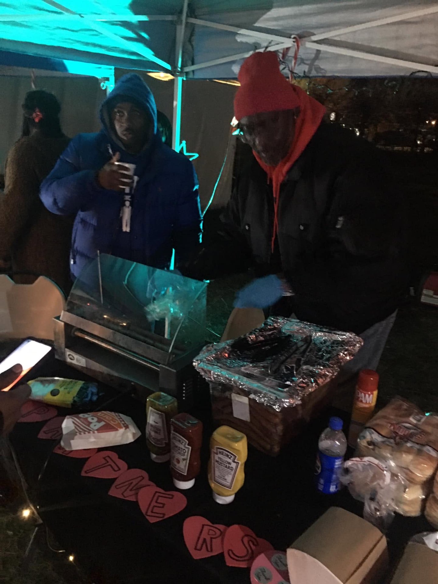 Two Brothas Inc. volunteers grilling hot dogs on the Partners table at Jingle Jam 2023