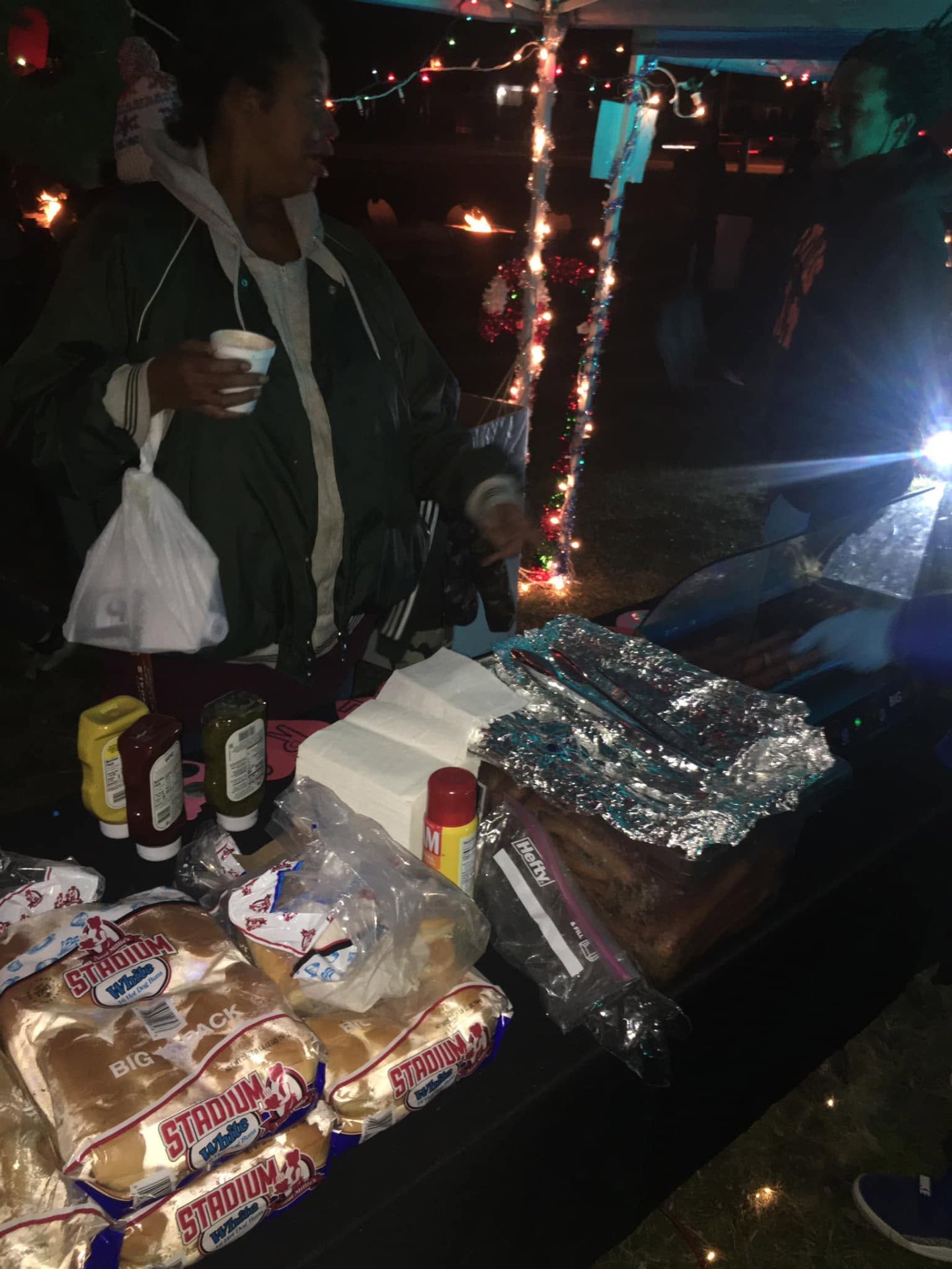 Volunteer serving free hot dogs and buns to community members at Brothas Inc. Jingle Jam 2023