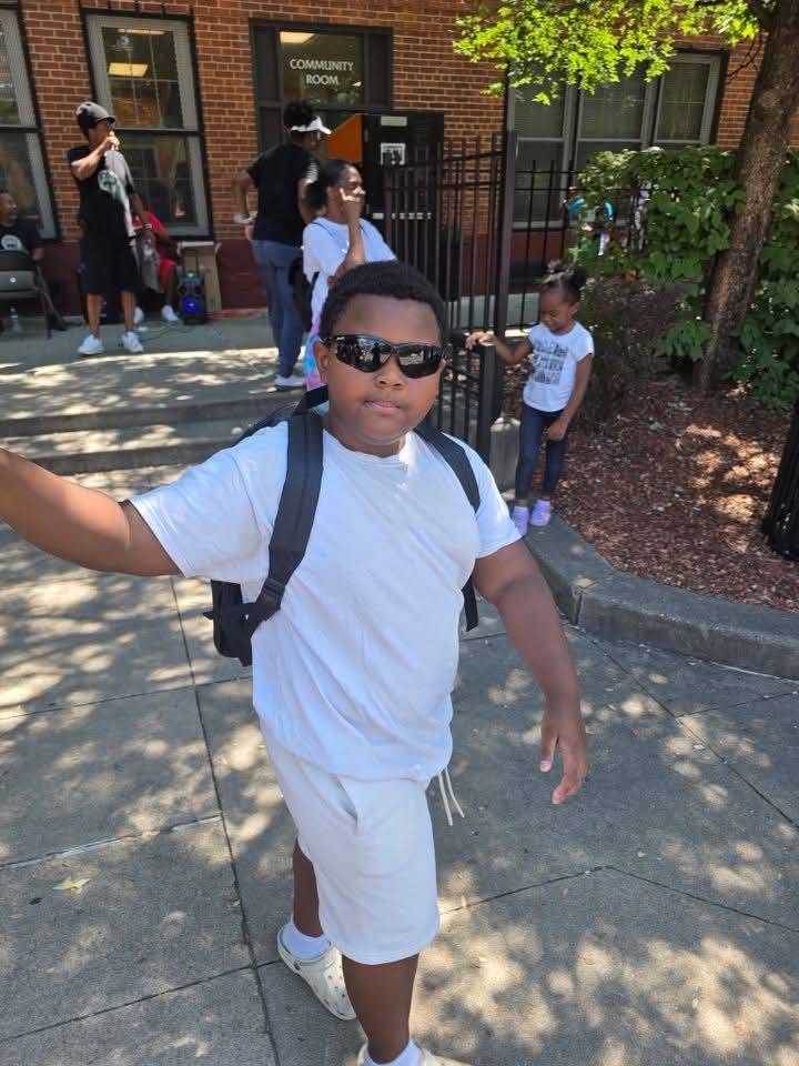 A boy in sunglasses showing off his new backpack at the 2025 Backpack Giveaway
