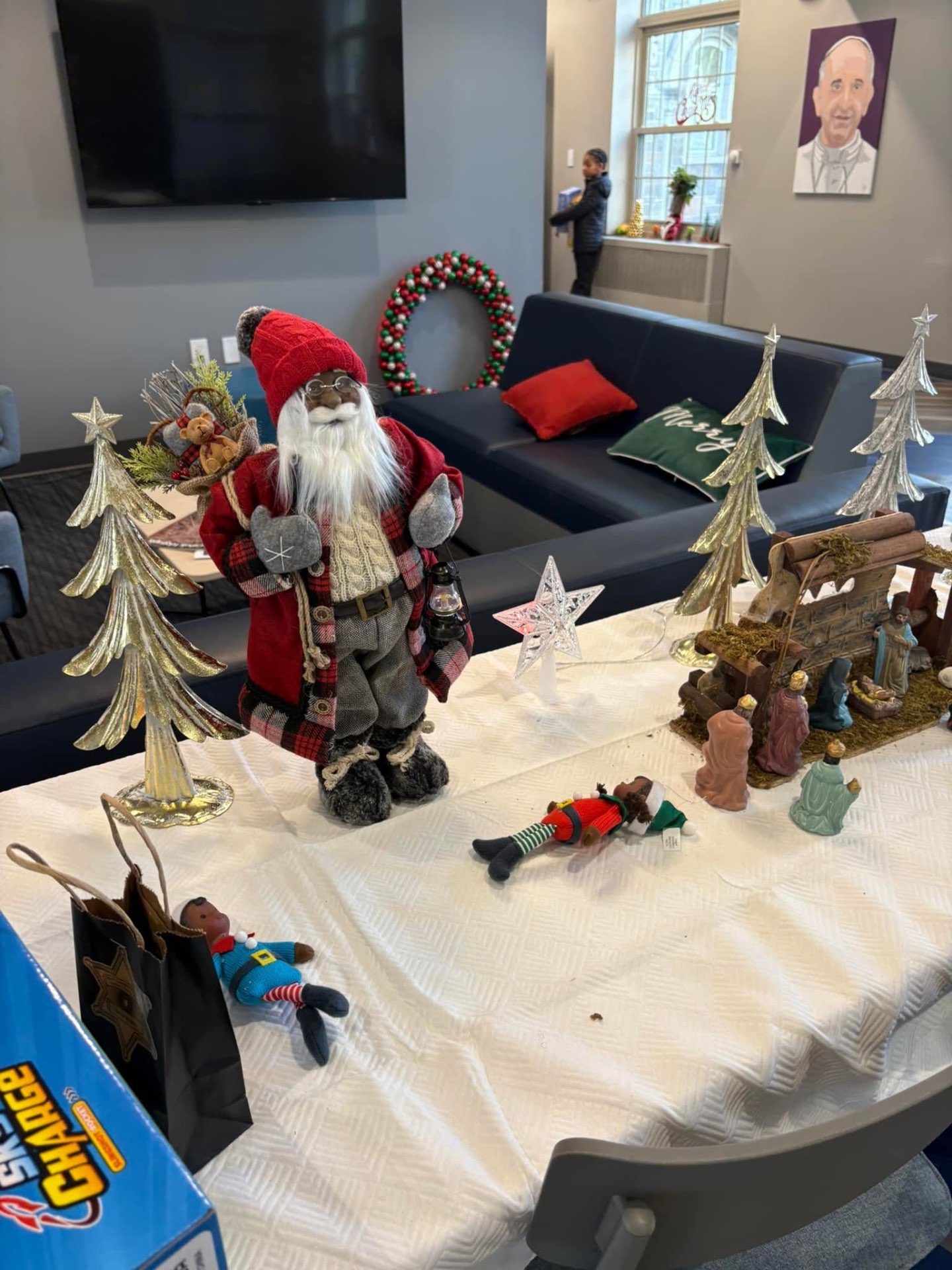 Decorated table with a Santa figure, silver Christmas trees and a nativity scene set up for Brothas Inc. Jingle Jam 2025