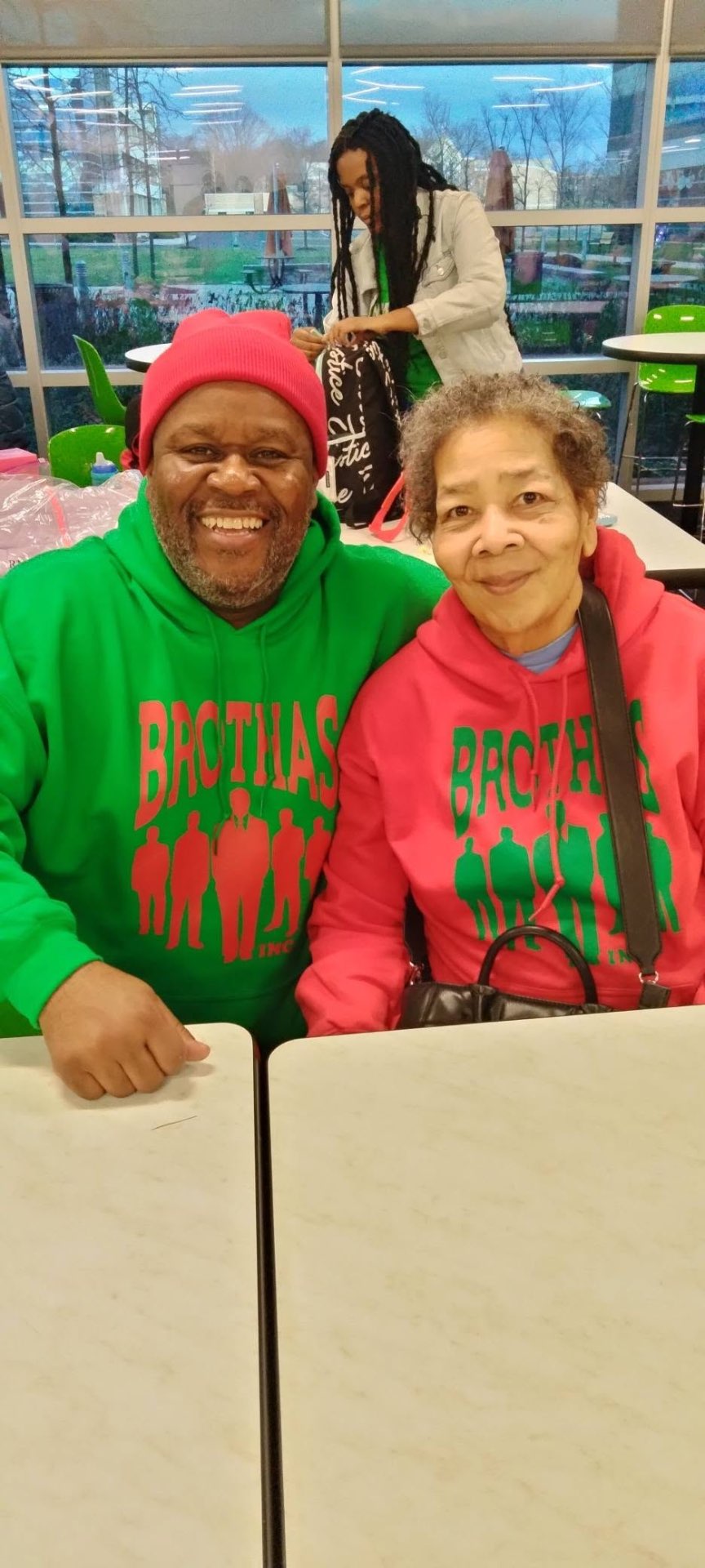 Couple in matching red and green Brothas Inc. hoodies at Jingle Jam 2024