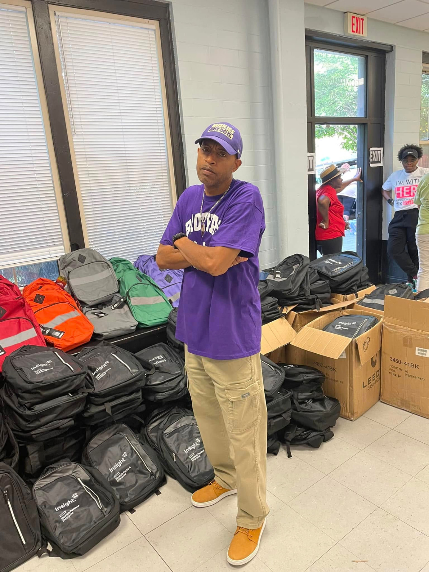 Brothas Inc. member standing beside dozens of donated backpacks stacked for the 2024 giveaway