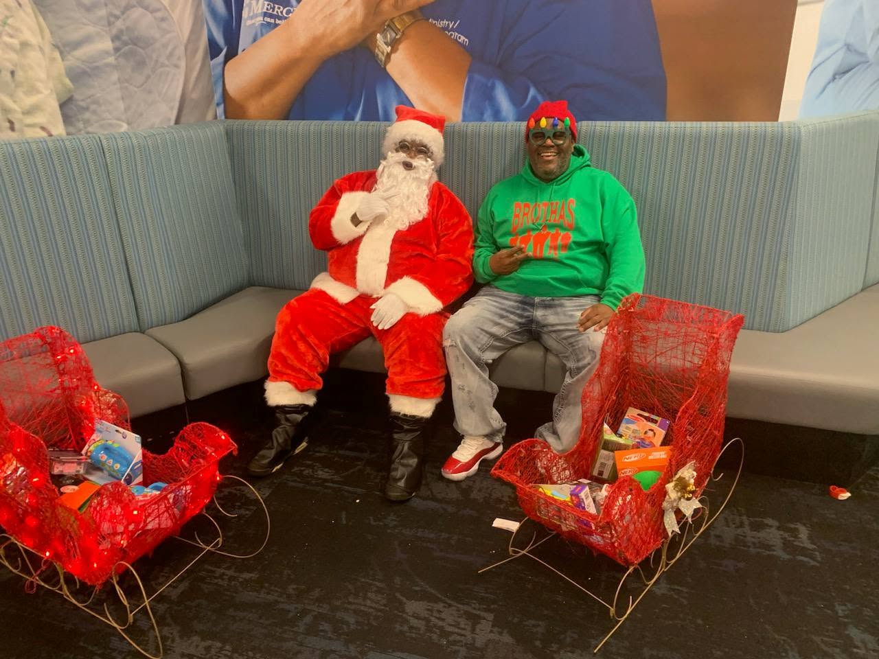 Santa and a Brothas Inc. elf posing with sleighs full of toys at Jingle Jam 2024