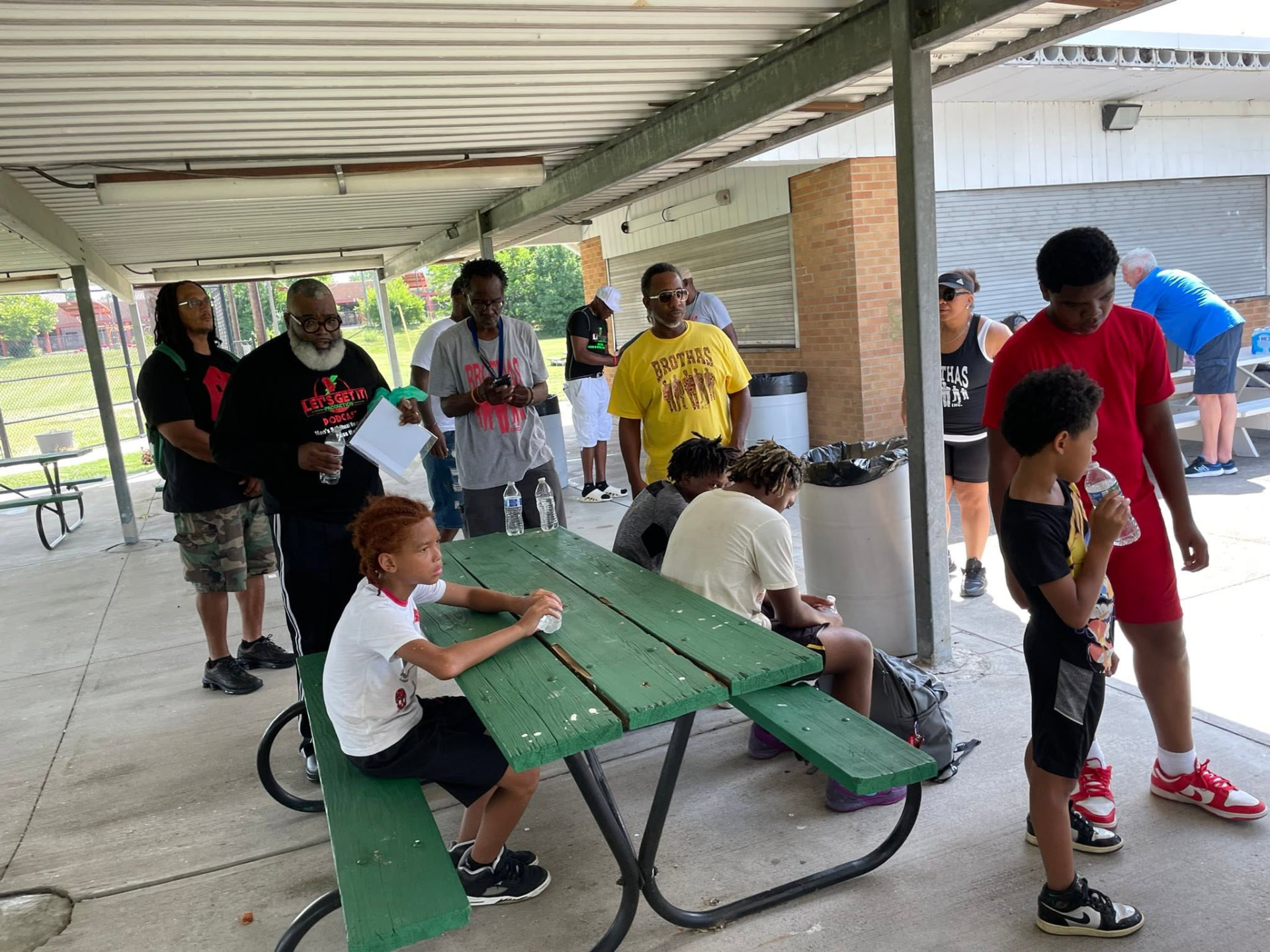 Mentors and youth gathered around picnic tables taking a water break at Saturday Hoops