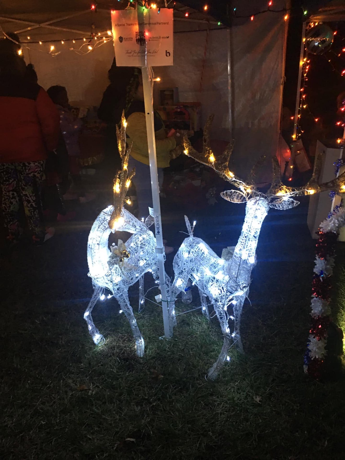 Two illuminated wire reindeer displayed under the partner sponsor sign at Brothas Inc. Jingle Jam 2023
