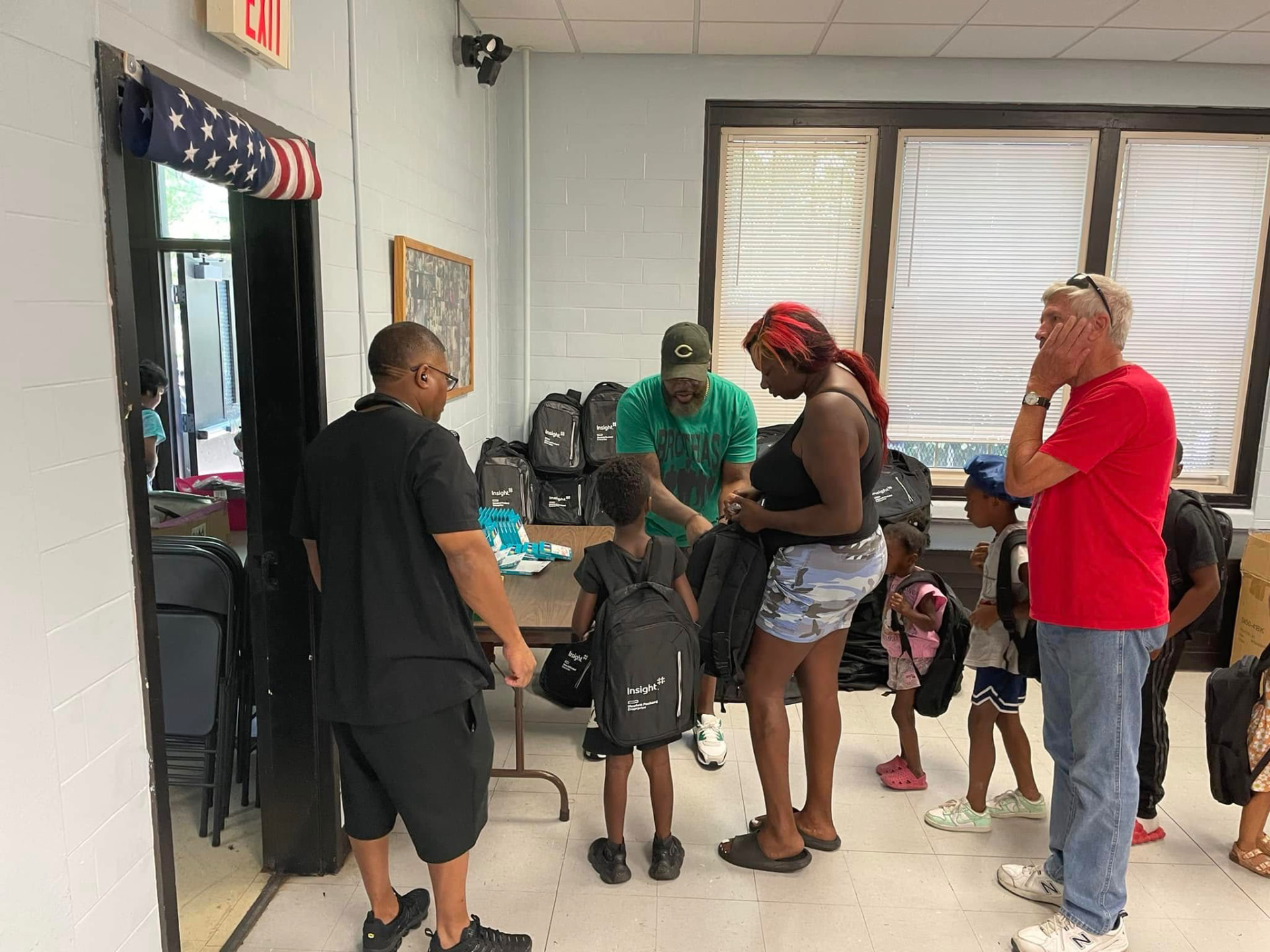 Brothas Inc. volunteers handing new backpacks to a family with young children at the 2024 Backpack Giveaway