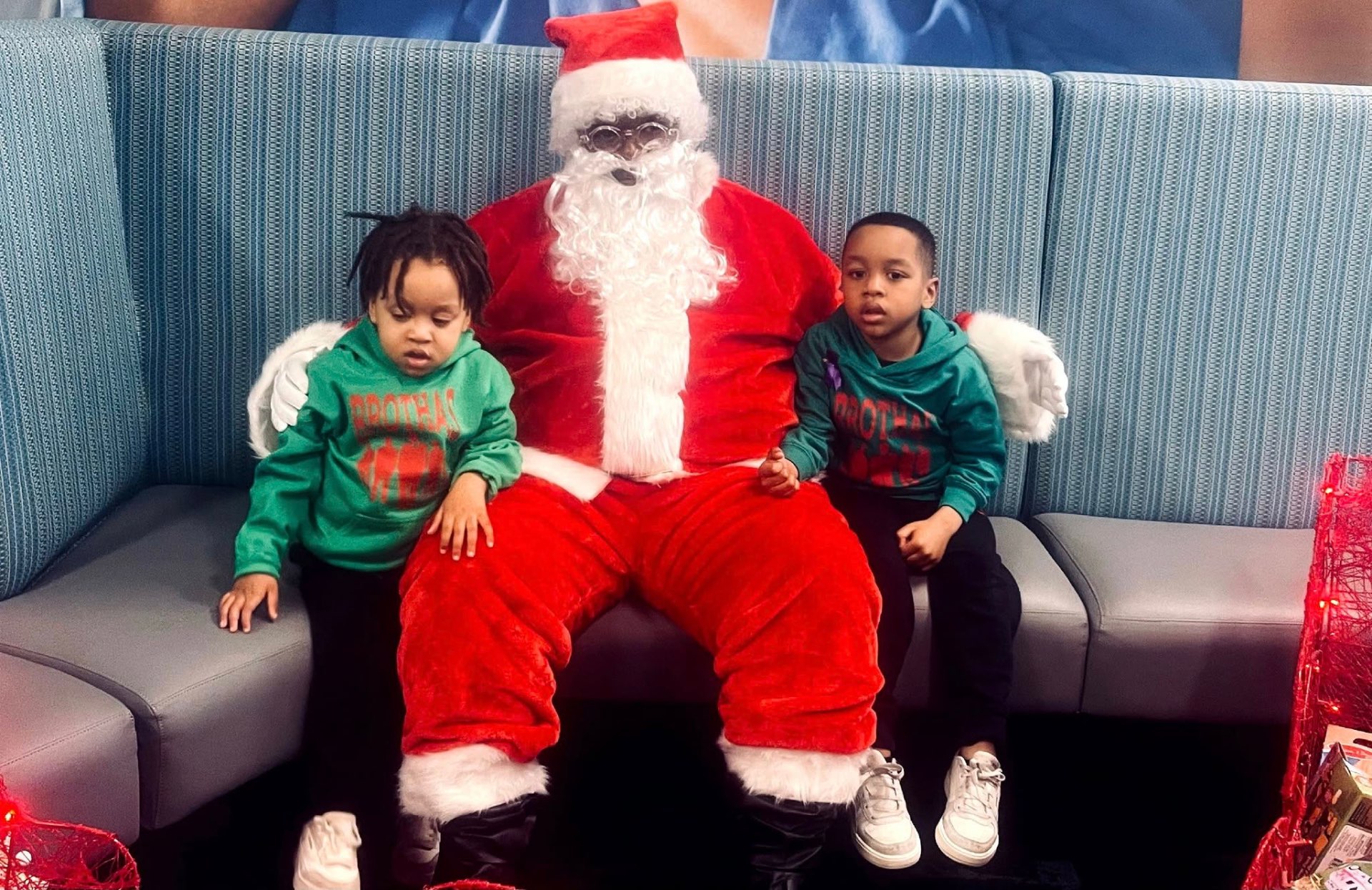 Two young children sitting with Santa at Brothas Inc. Jingle Jam 2024