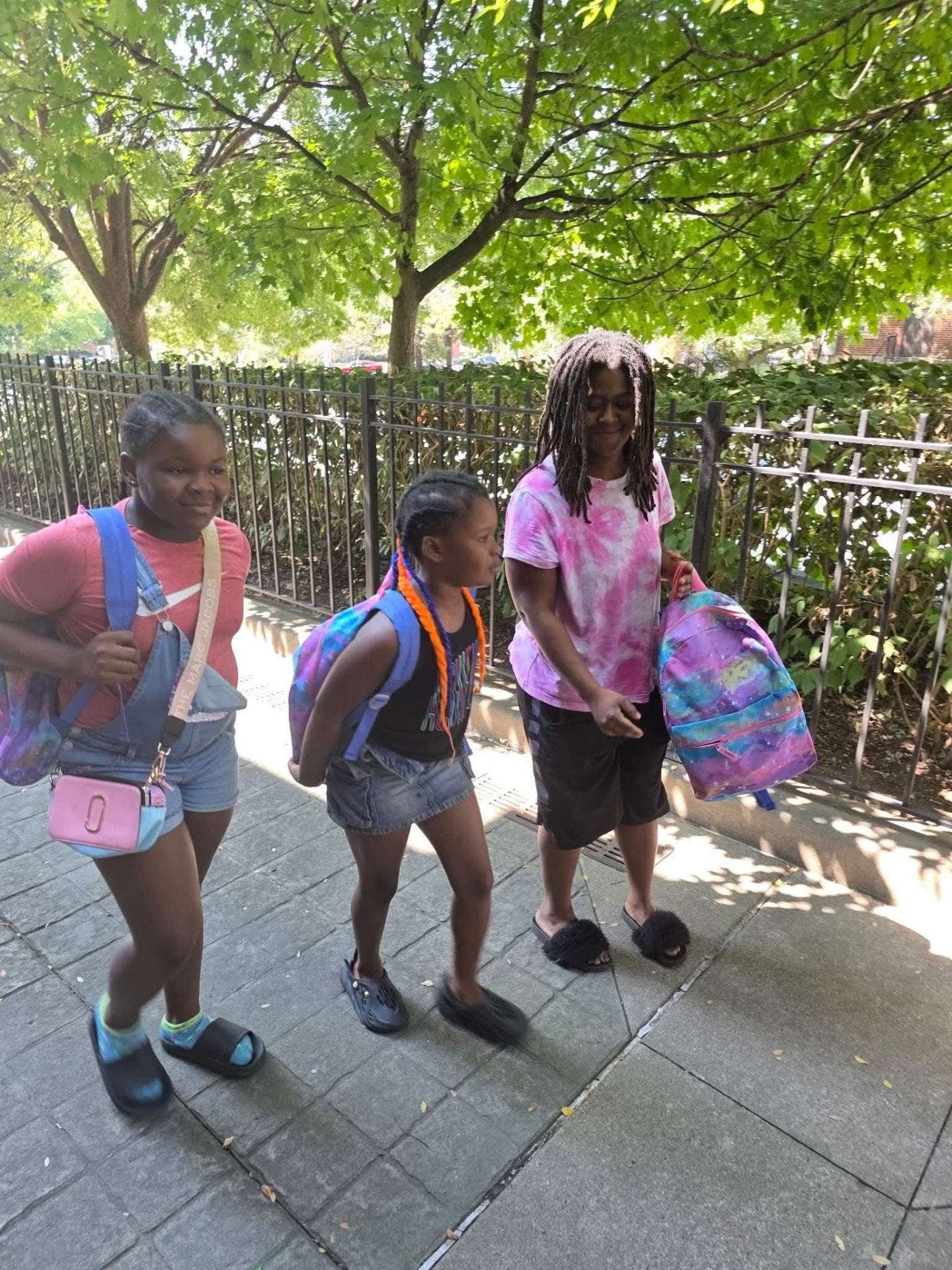 A family walking home along the sidewalk with new backpacks from the 2025 giveaway