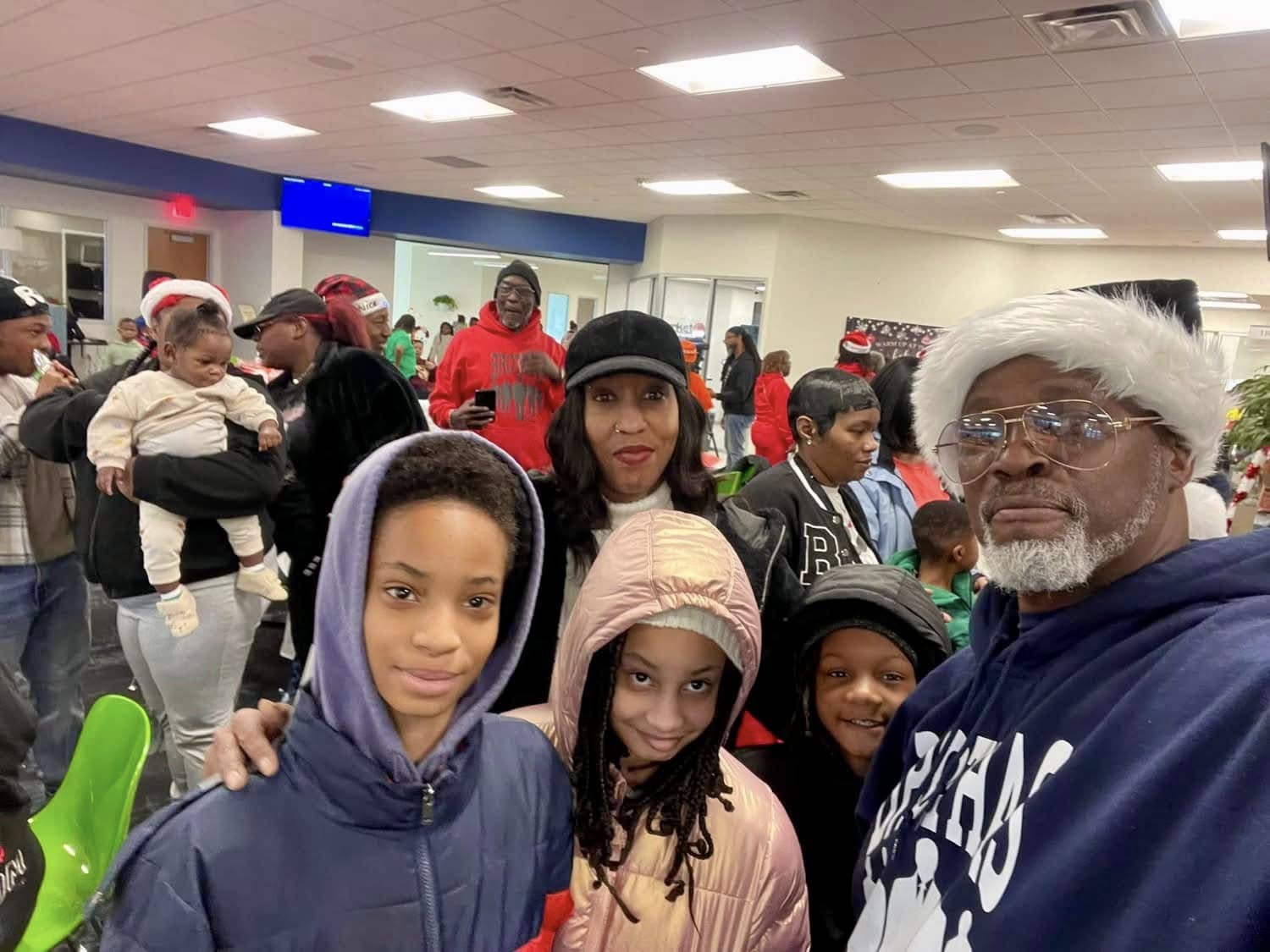 Grandfather in Santa hat and Brothas Inc. hoodie posing with grandchildren at Jingle Jam 2024