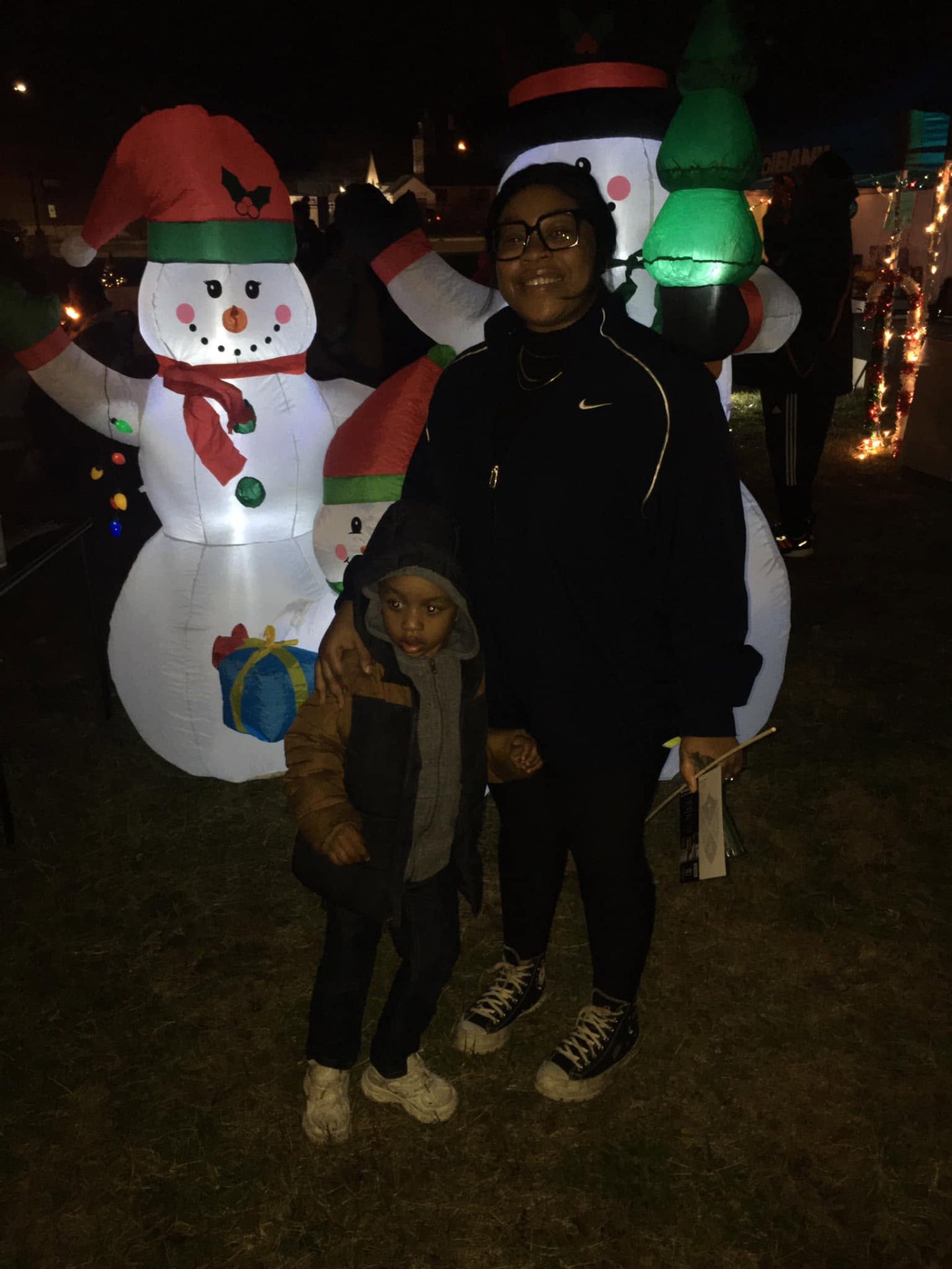 Mother and son posing in front of glowing inflatable snowmen at Brothas Inc. Jingle Jam 2023