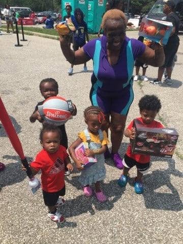 Volunteer with kids holding basketballs and toys at KidsFest