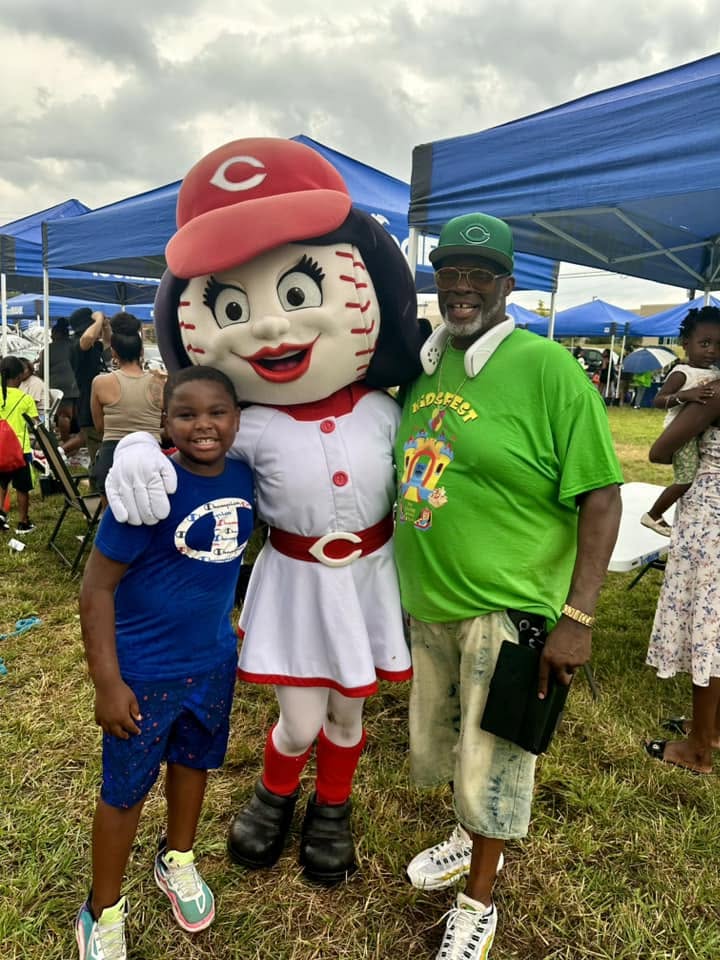 Kid and mentor posing with Reds mascot Rosie Red at 2nd KidsFest