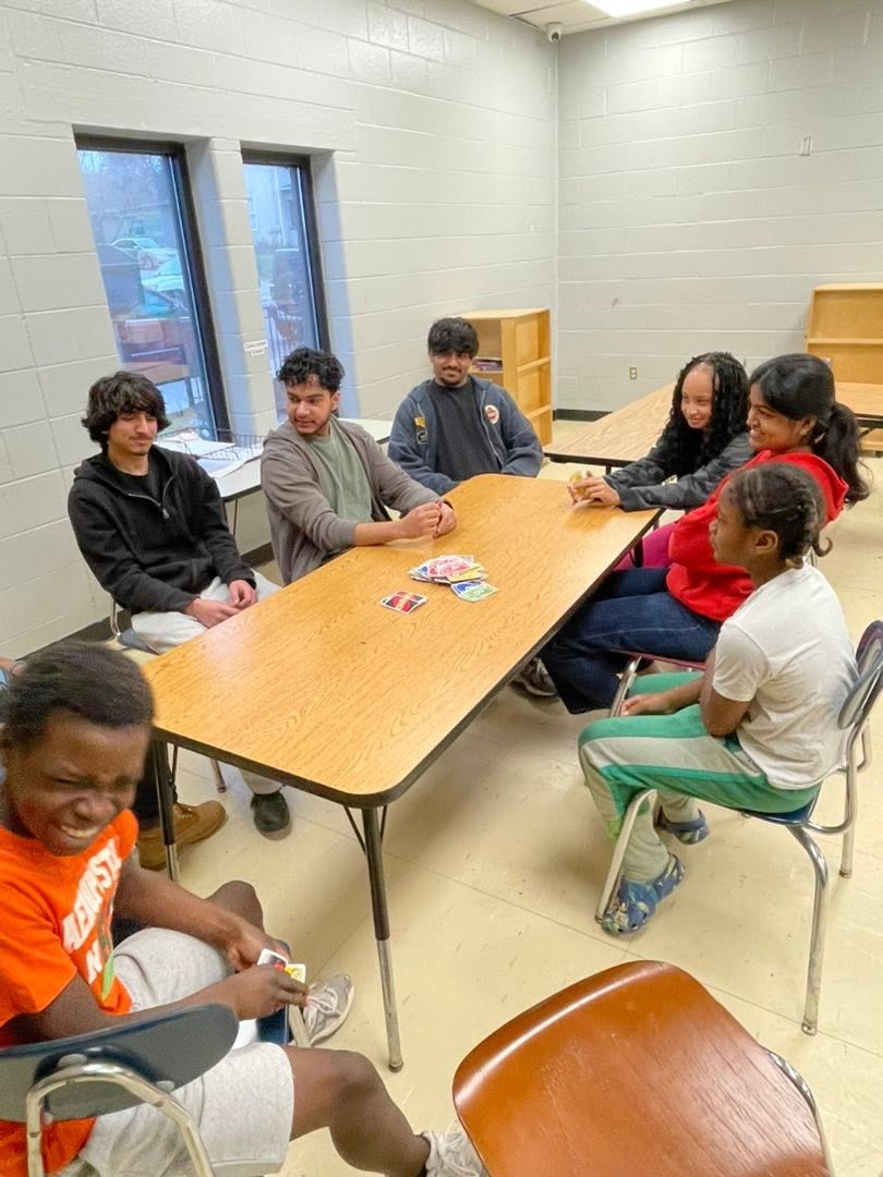 Teens playing a card game around a table during a Saturday Hoops session