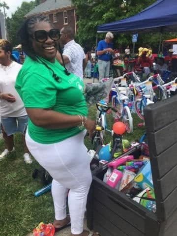 Volunteer beside a bin of toys and bikes at KidsFest
