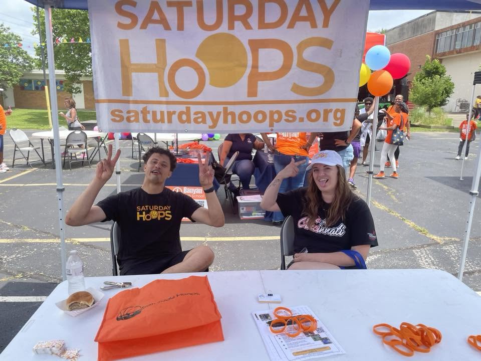 Saturday Hoops volunteers throwing peace signs at their KidsFest booth